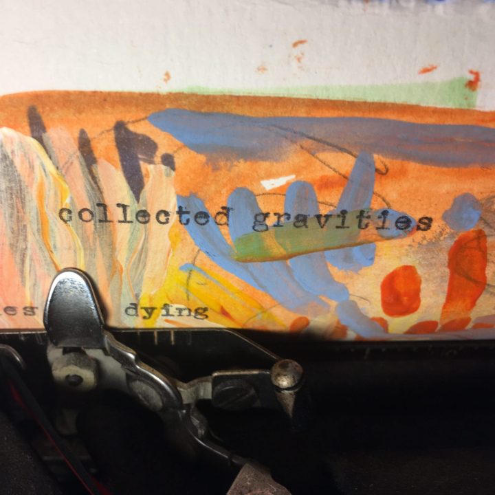 "collected gravities" typed with a typewriter on a colorfully painted piece of paper